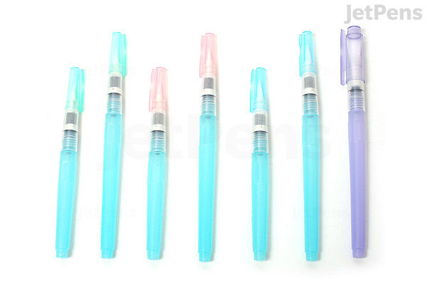 Seven Kuretake Water Brush pens in various sizes and colors, arranged in a row on a white background. The pens have transparent caps and colored barrels in shades of blue, pink, and purple.