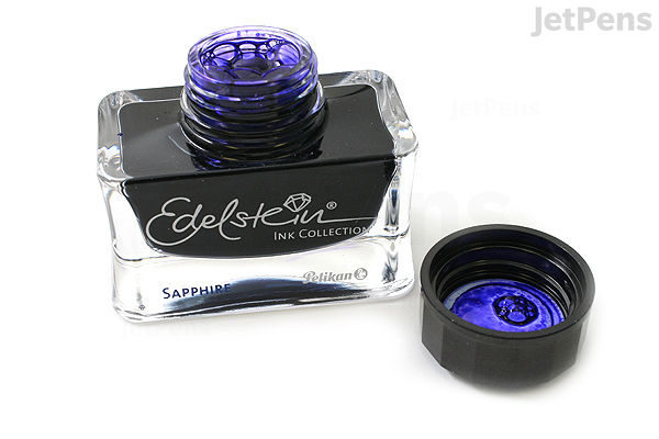 A 50 ml bottle of Pelikan Edelstein Sapphire blue ink with the cap removed and placed beside it, showing the vibrant blue ink inside the bottle and on the inside of the cap.
