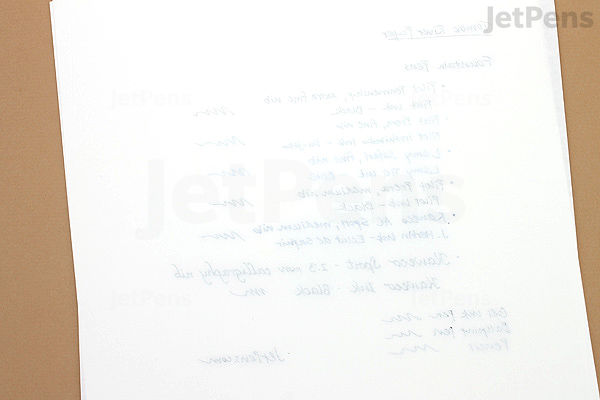 A close-up photo of a white B5-sized notebook page from a Tomoe River 52 gsm Kanso Notebook, showing faint blue handwritten text and ink swabs in various shades of blue and gray. The paper appears smooth and thin, with minimal ink bleed-through.
