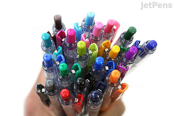 A hand holding a large assortment of Zebra Sarasa Clip Gel Pens in various colors, all with 0.5 mm tips. The pens have clear barrels and colored clips matching the ink color.