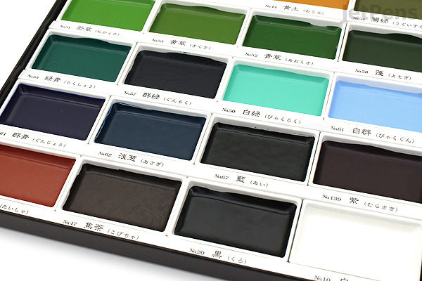 Close-up of a Kuretake Gansai Tambi 24-color watercolor palette showing vibrant, rectangular paint pans arranged in rows inside a white case.