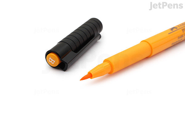 A Faber-Castell PITT Artist Pen with a brush tip in deep red color (223) shown uncapped, with the black cap placed beside it. The pen body is orange with branding and product details.