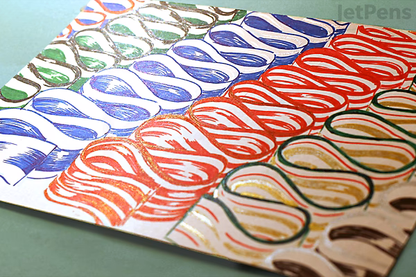 Several sheets of paper display repeated wavy line patterns drawn with Uni-ball Signo Broad UM-153 gel pens in silver ink, shown in blue, red, and black colors.