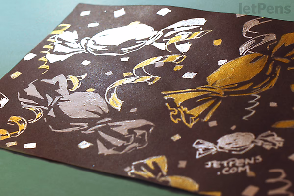 A dark brown sheet of paper with various silver ink sketches and doodles, including abstract shapes, faces, and handwritten text, created using a Uni-ball Signo Broad UM-153 gel pen.