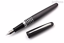 A Pilot Metropolitan Retro Pop fountain pen in gray with a houndstooth pattern on the barrel near the nib, shown uncapped with the medium italic nib visible. The cap is placed beside the pen.