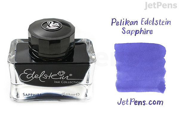 A 50 ml glass bottle of Pelikan Edelstein Sapphire fountain pen ink with a black cap. Next to the bottle is a swatch of the ink color, a rich blue-purple shade, labeled "Pelikan Edelstein Sapphire" and "JetPens.com."
