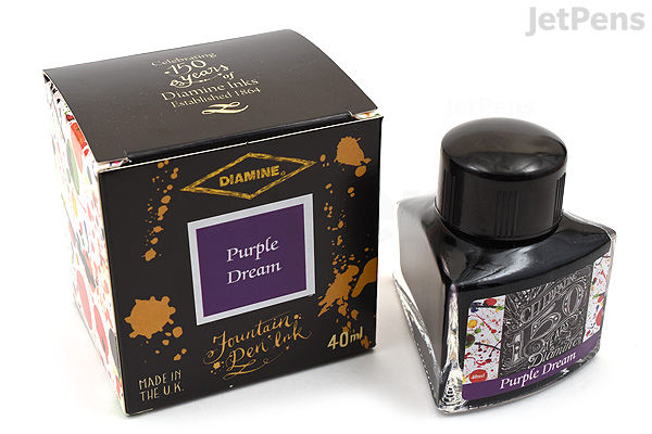 A 40 ml bottle of Diamine Purple Dream ink alongside its black and gold decorative box, commemorating the brand's 150th anniversary. The box features a purple label with the ink name, and the bottle has a black cap with a label showing the same design.