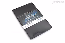 A black Stillman & Birn Nova Sketchbook with a softcover, measuring 5.5 by 8.5 inches, shown in its original packaging with a white paper band around it.