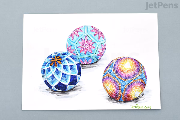 A drawing of three colorful spherical objects with intricate geometric patterns, created using fine lines and vibrant colors including blue, pink, yellow, and purple. The spheres are arranged on a white background.