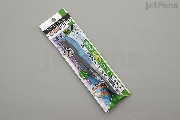 Packaging of a Tombow Fudenosuke Brush Pen in soft black, featuring Japanese text and colorful design elements on a white and green background.