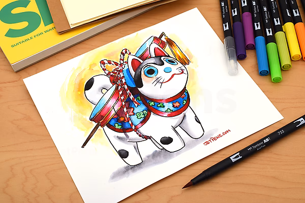 A colorful drawing of a white cat wearing a vibrant, patterned outfit and holding a paintbrush, created with Tombow Dual Brush Pens. Several pens in various colors are scattered nearby on a wooden surface.