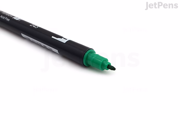 A Tombow Dual Brush Pen with a green brush tip, shown diagonally on a white background. The pen body is black with white text.