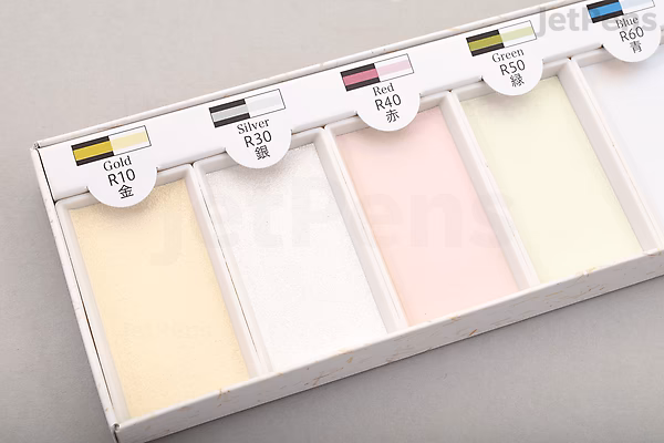 Close-up of Boku-Undo Gansai Watercolor Palette in the Aurora 6-color set, showing four rectangular pans with soft pastel shades: pale yellow, white, light pink, and light cream, each labeled with color names and codes.