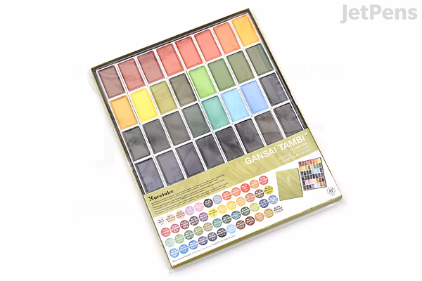A Kuretake Gansai Tambi watercolor palette featuring 48 vibrant colors arranged in six rows within a rectangular case. The palette includes a color guide with labeled swatches beneath the paint pans.