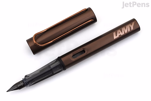 A LAMY Lx Marron fountain pen with a fine nib, shown uncapped. The pen has a sleek, metallic brown body with a matching brown cap featuring an orange clip. The brand name "LAMY" is visible on the pen barrel.