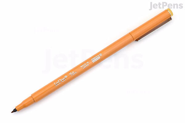 Image of a Marvy Le Pen Flex Brush Pen in ochre color, shown with the cap off to reveal the flexible brush tip. The pen body is orange with white text.