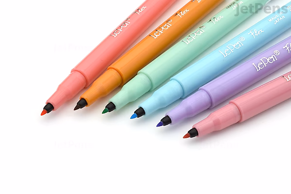Set of six Marvy Le Pen pastel flex brush pens arranged diagonally, showing fine brush tips and colored barrels in soft shades.