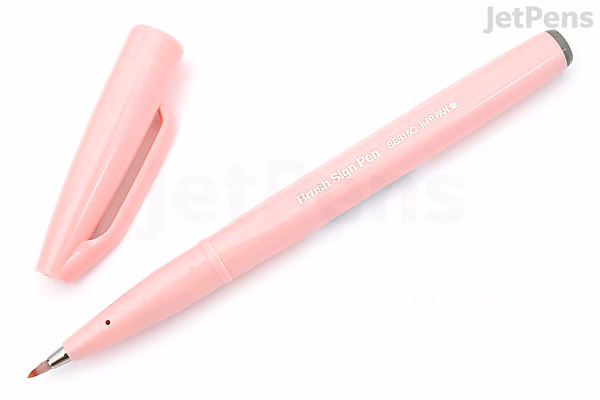 A pale pink Pentel Fude Touch Brush Sign Pen with its cap removed and placed beside it, showing the fine brush tip.
