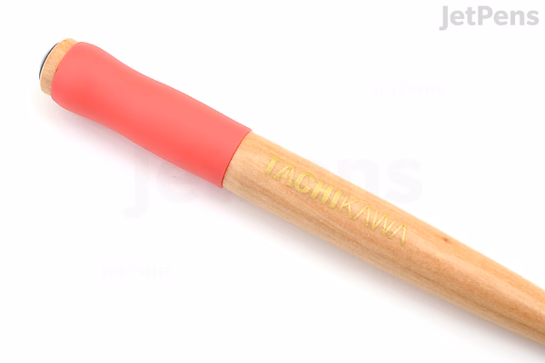 Close-up image of a Tachikawa T-36 nib holder featuring a natural wood handle and a bright pink rubber grip near the metal nib end.