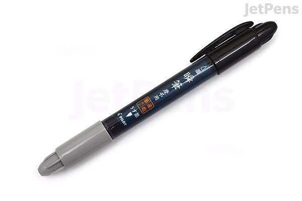 A double-sided Pilot Shunpitsu Pocket Brush Pen with black and gray ink, featuring a brush tip on one end and a fine tip on the other. The pen body is black with white and orange Japanese text and a gray cap on the fine tip end.