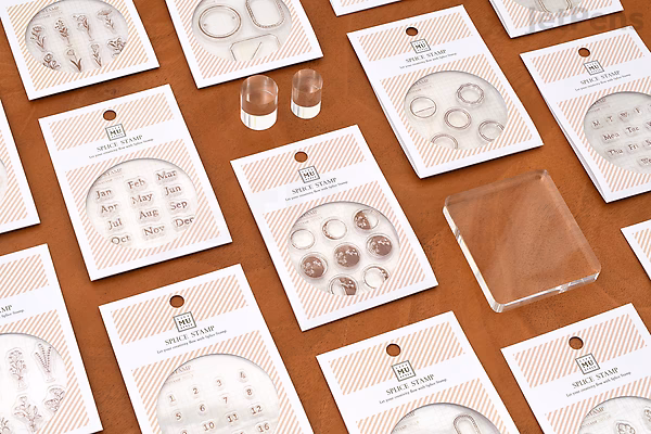 Flat lay of multiple clear stamp sets in plastic packaging arranged on a brown surface, each featuring various circular and floral designs for crafting and scrapbooking.
