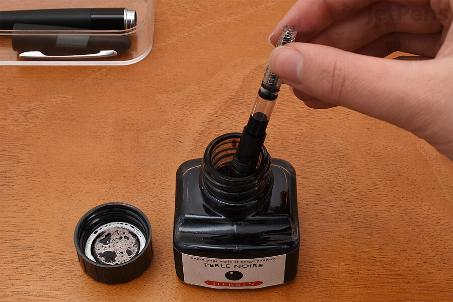 2. Immerse all of the nib and part of the grip section in the ink. Twist the knob in the other direction to retract the piston and draw in ink. Repeat as necessary until the converter is full.