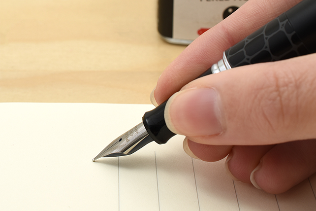 Grasp the grip section above the nib with your fingers. Do your best to hold your pen in a relaxed position.