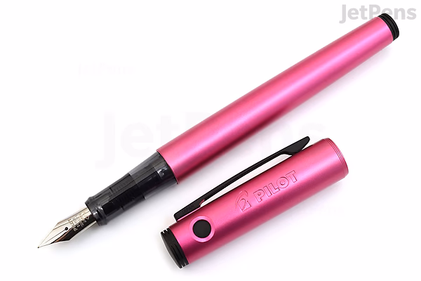 A pink Pilot Explorer fountain pen with a fine nib, shown uncapped with the cap placed beside it. The pen has a sleek, metallic finish and a black clip on the cap.