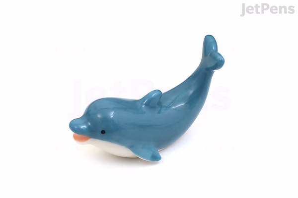 A small, glossy blue ceramic pen rest shaped like a dolphin with an orange tongue sticking out.