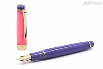 A Sailor Pro Gear Slim fountain pen in a vibrant purple color with gold accents, shown uncapped with the cap standing upright beside it. The pen features a 14k extra fine nib.