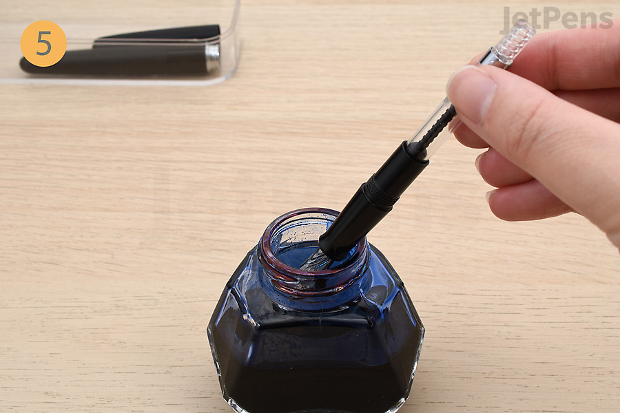 Dip the fountain pen in an ink bottle.