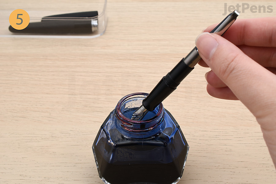 Dip the fountain pen in an ink bottle.