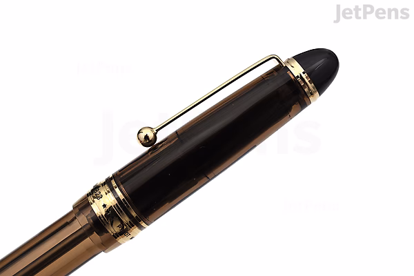 Close-up image of the cap of a Pilot Custom 823 fountain pen in amber brown with gold accents and a black finial.