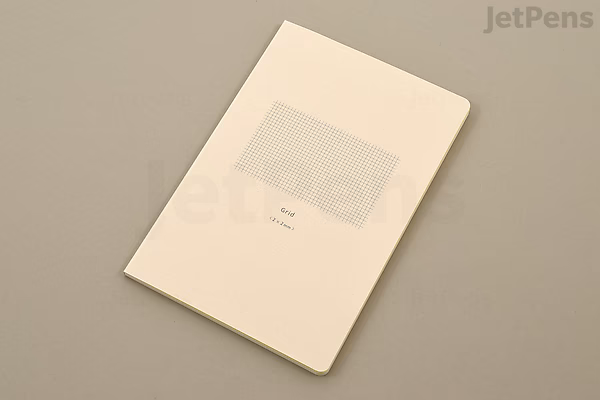 A beige Midori Yuru Log Notebook in B6 size with MD Thick paper featuring a 2 mm grid pattern. The notebook has a simple, minimalist cover with a small rectangular label area in the center.