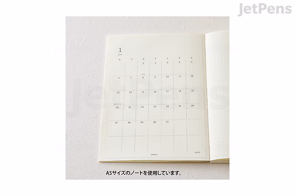Sheet of Midori MD Diary 2025 large calendar stickers with a minimalist grid layout, designed for planners or diaries, shown partially peeled from a white backing.