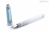 A sleek, light blue and white fountain pen with a silver clip and a 14k extra fine nib, displayed with its cap removed and placed upright beside it. The pen is a limited edition Sailor Pro Gear Slim model inspired by the Sapporo Snow Festival.