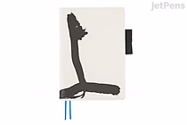 Cream Hobonichi Techo Cousin A5 cover with bold black abstract brushstroke design (Yuichi Inoue "Jo"), black pen loop at right and two blue ribbon bookmarks.