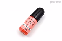 Small pink Midori Yuru Log paintable stamp refill bottle with black cap and Japanese label, photographed at a slight angle on a white background.